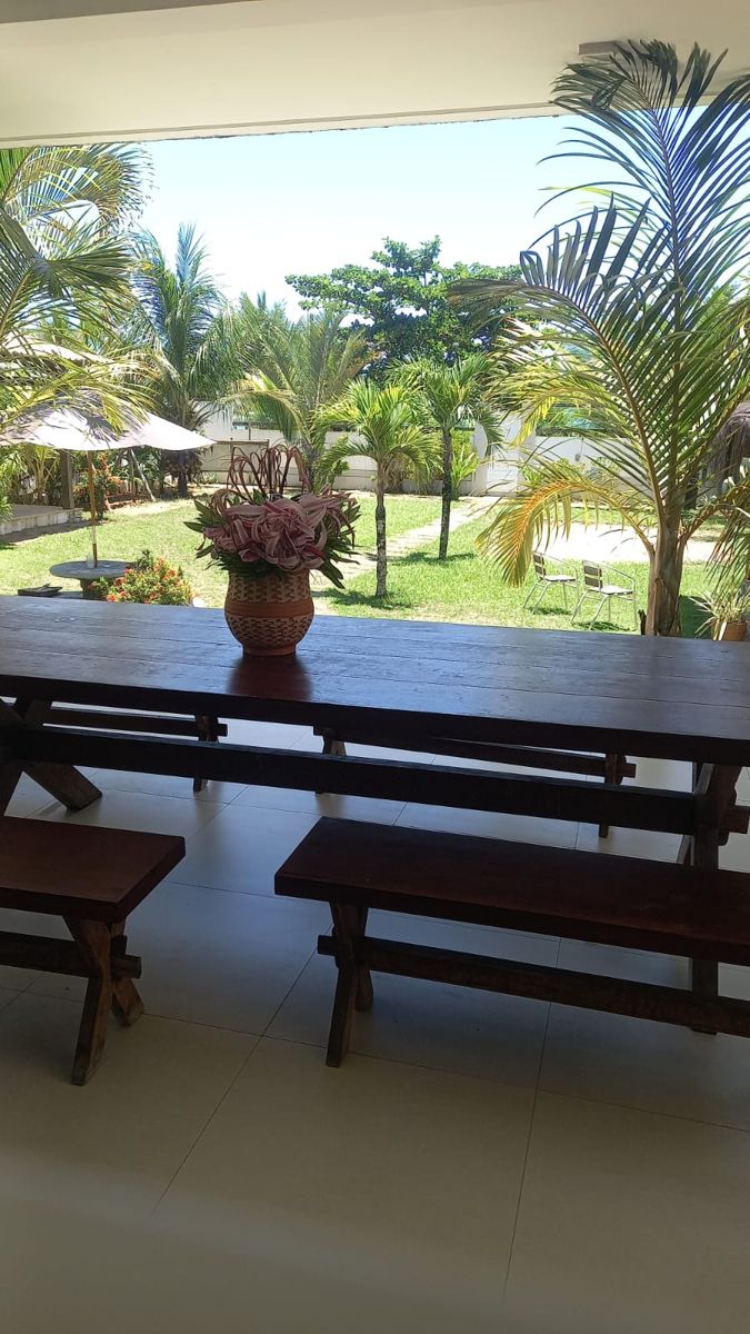 Área coberta com mesa de madeira voltada para o jardim