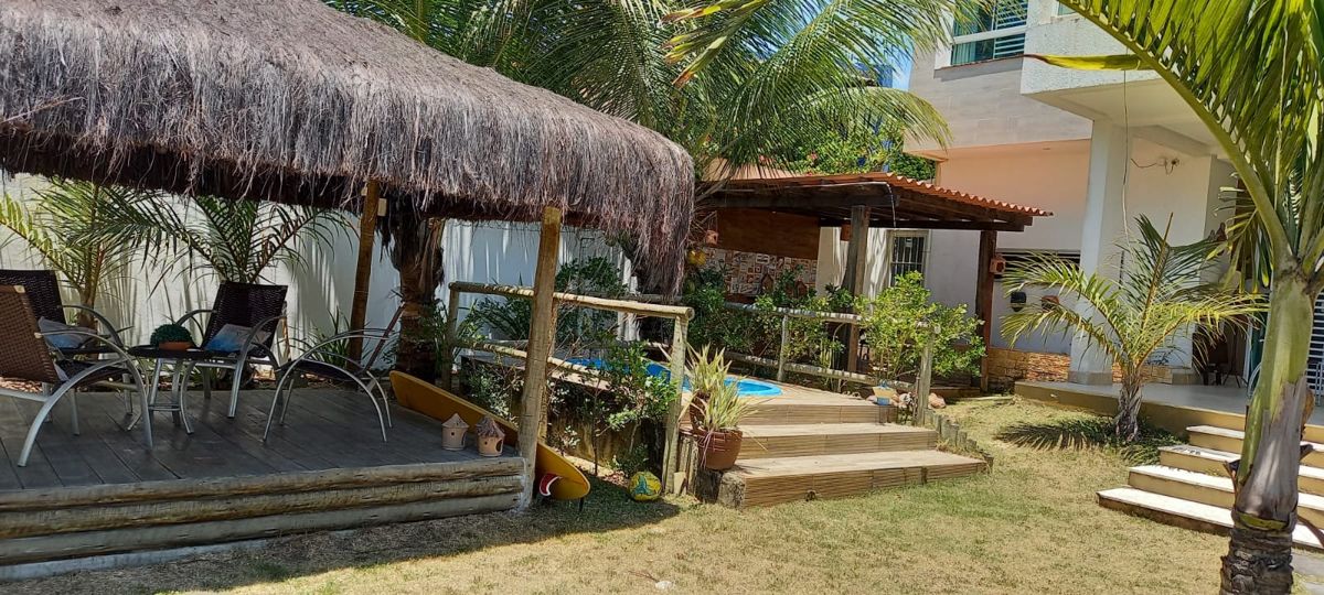 Deck com palhoça, cadeiras e piscininha ao fundo