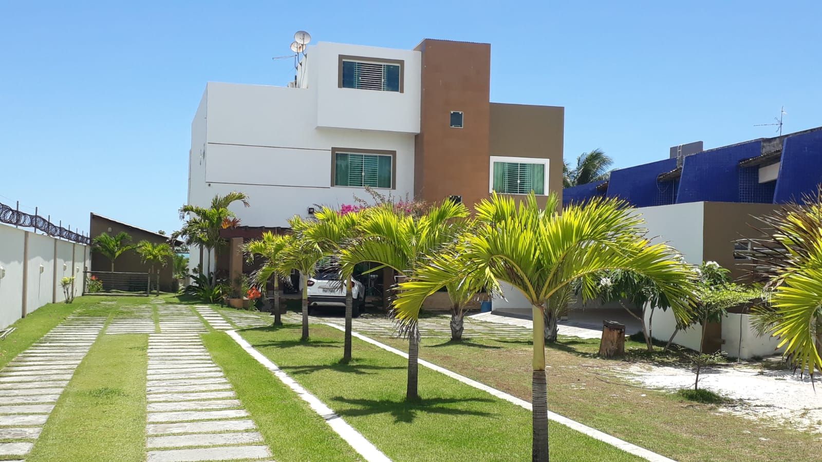Fachada da Vivenda Canoa, casa para temporada em Guaibim, com jardim de palmeiras