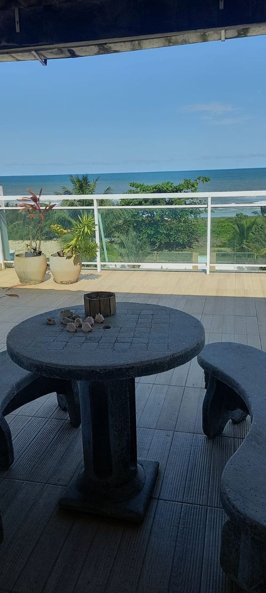 Terraço coberto com mesa de pedra e vista para o mar